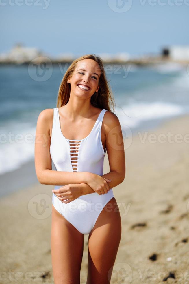 blonde Frau mit schönem Körper im Schwimmer an einem tropischen Strand foto