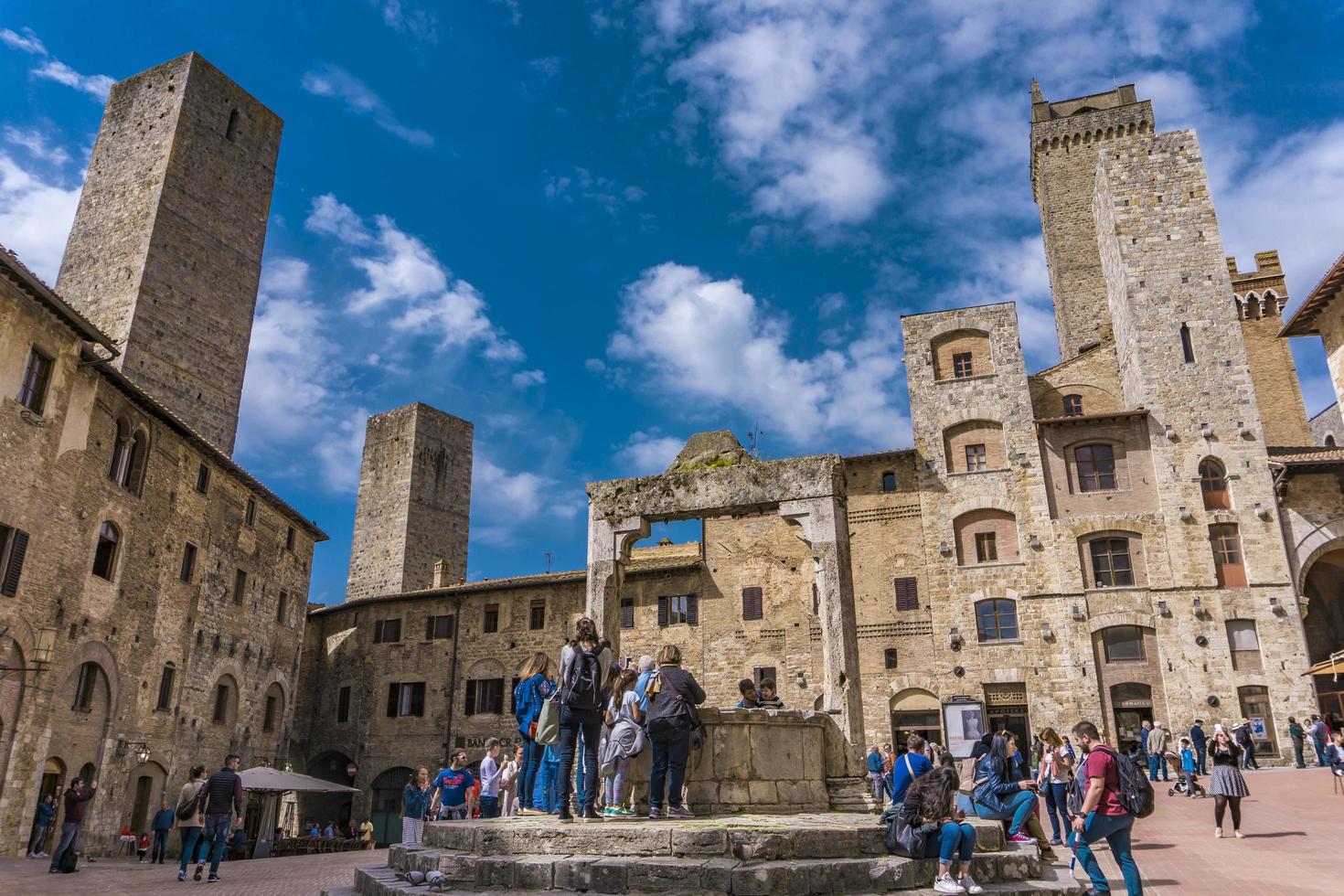 San Gimignano, Italien, 8. April 2018 - Unbekannte Personen auf der Piazza della Cisterna in San Gimignano, Italien. Das historische Zentrum von San Gimignano ist seit 1990 als UNESCO-Weltkulturerbe ausgezeichnet. foto