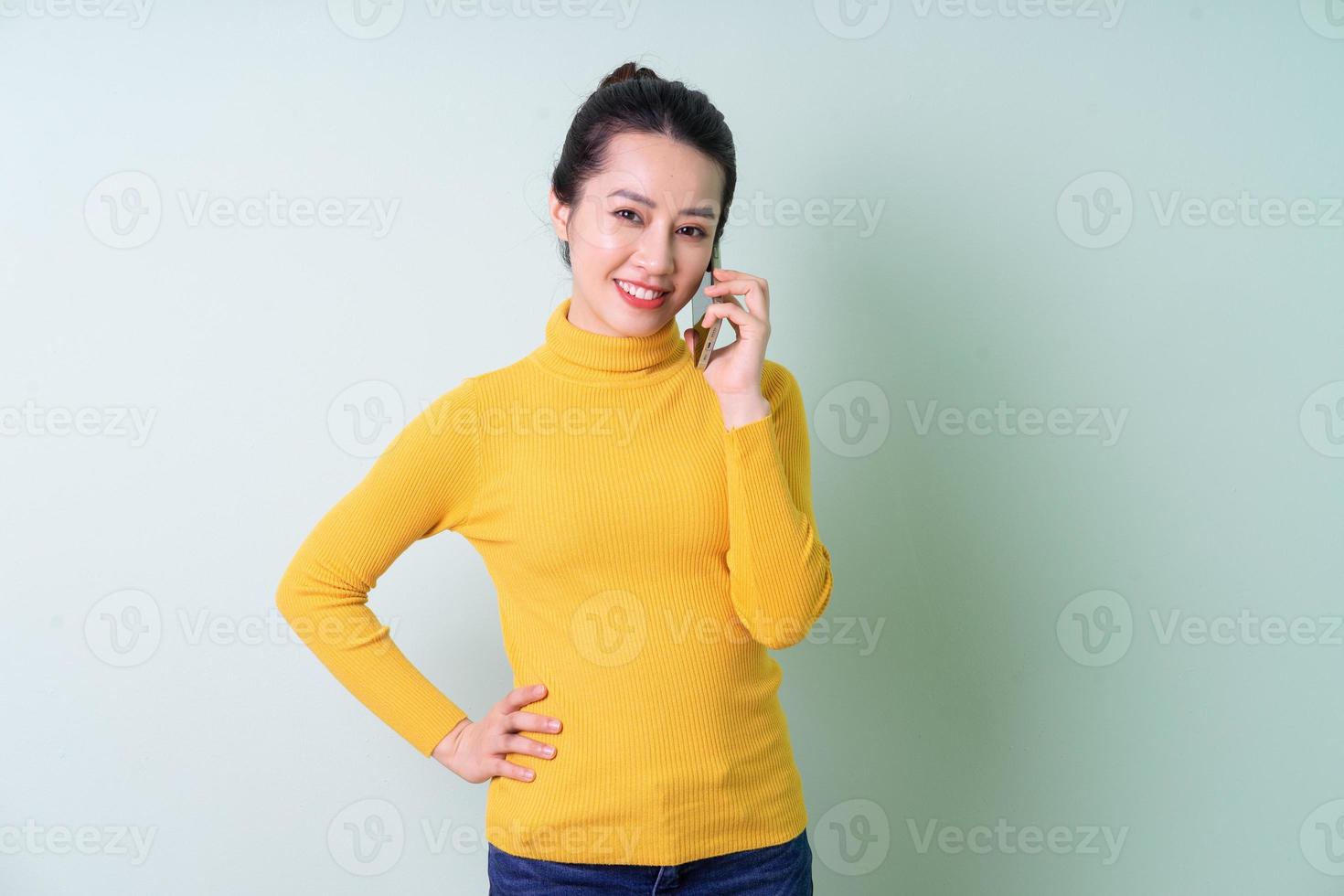 schöne junge asiatische frau mit pullover auf grünem hintergrund foto