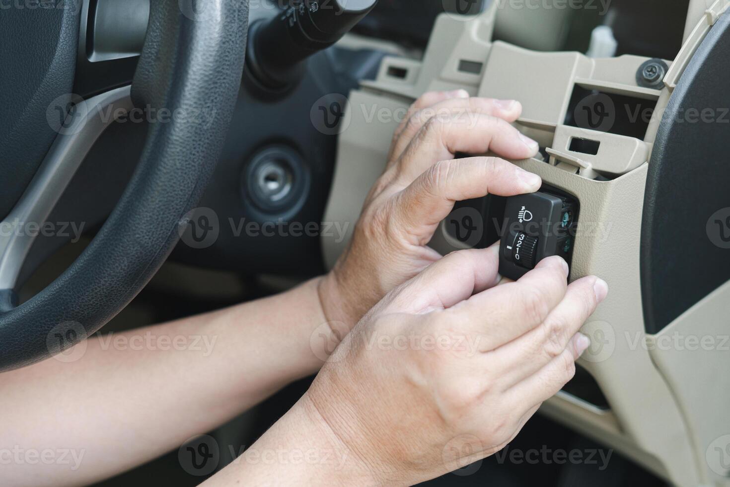 Nahaufnahme eines Handtechnikers, der den Autoscheinwerferschalter auf Wartung überprüft, um sicherzustellen, dass die Ersatzteile in der Werkstatt ausgetauscht werden müssen foto