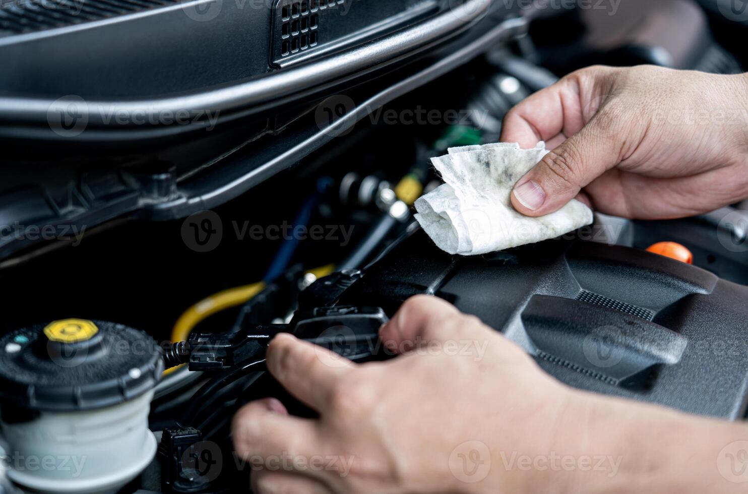 Zuhause Bedienung Auto Konzept ein Mann verwenden Stoff Reinigung Motor Öl beflecken und öffnen das Öl Deckel von Motor Motor- Basic Überprüfung und Instandhaltung Konzept foto