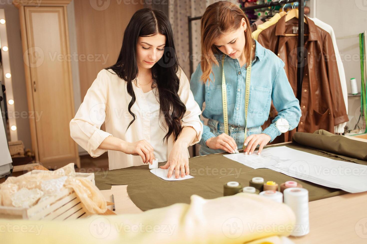 Näherinnen machen skizzieren, Muster auf Stoff. Atelier, Schneiderei von Individuell Kleidung, klein Geschäft. Prozess von Arbeit im Arbeitsplatz. foto