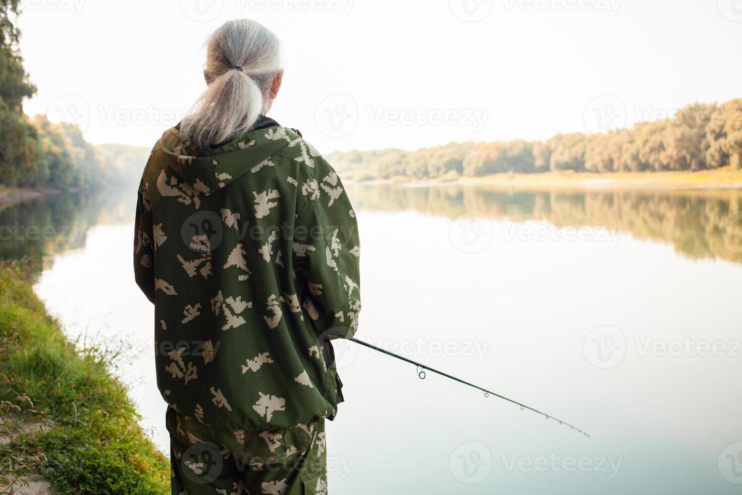 Senior Konzept. Rentner Fische auf das Fluss im seine schonen Zeit. ein nützlich Hobby, draussen Aktivitäten im alt Alter. Kopieren Raum. Rückseite Aussicht foto