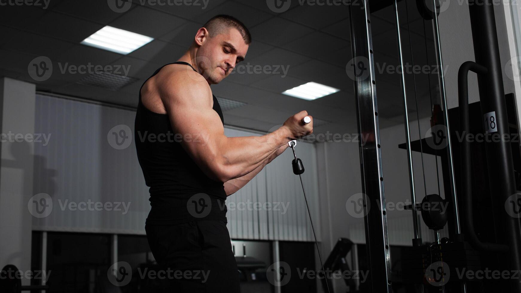 Porträt von ein Athlet, ein Sport Mann Trainer tut ein Übung auf Simulator im das Fitnessstudio. gesund aktiv Lebensstil, schüttelt Muskeln. muskulös Schultern foto