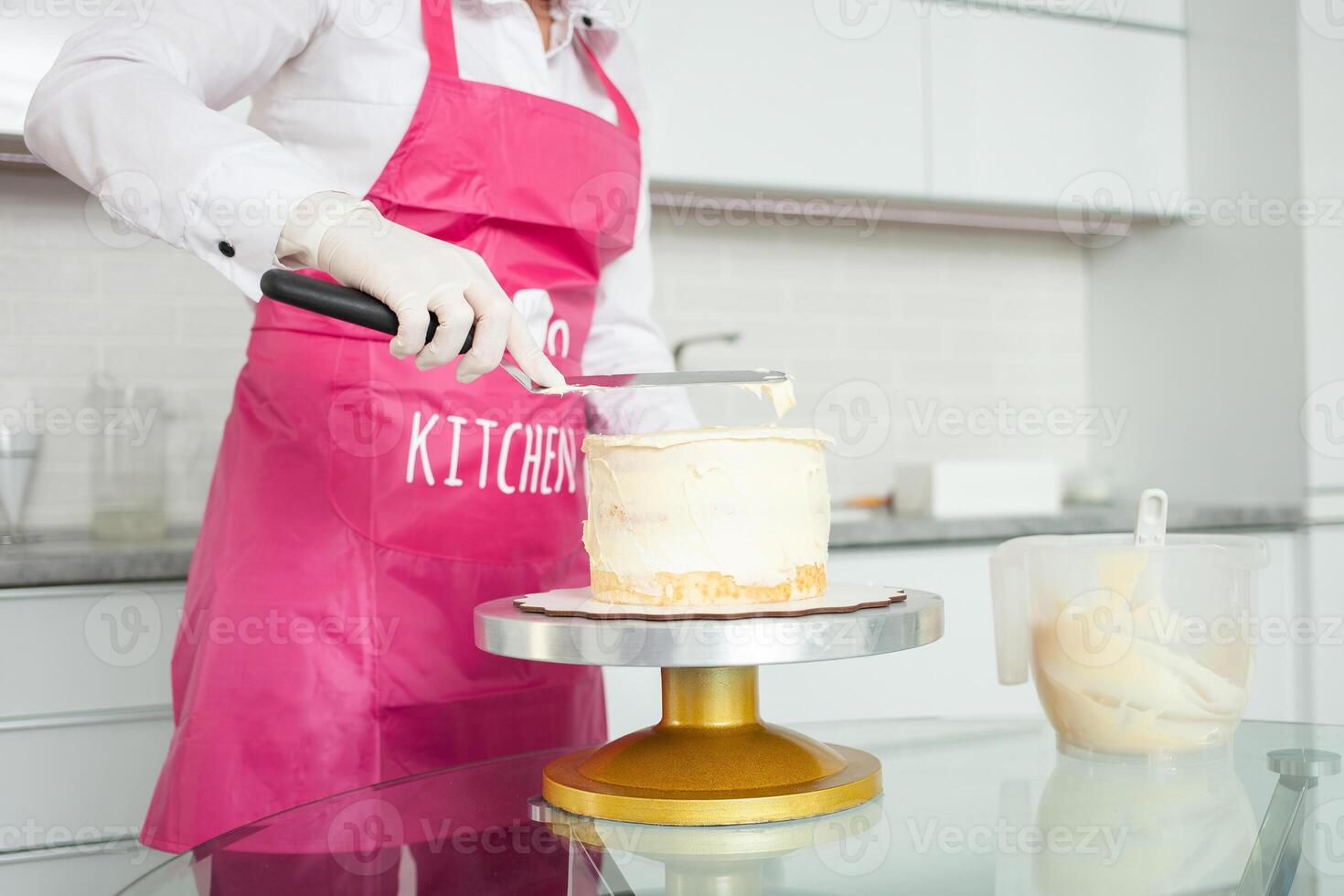behandschuhte Gebäck Koch dekoriert Kuchen mit Weiß Schokolade. schön hausgemacht Kuchen. Schürze foto