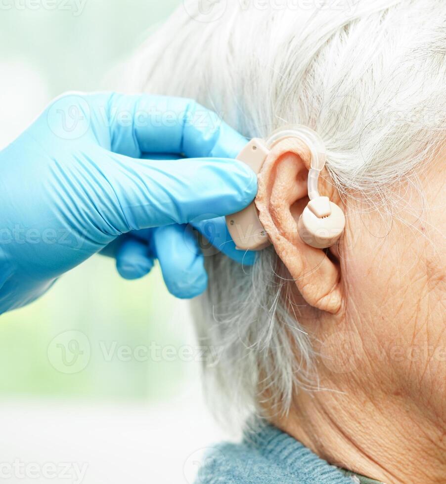 Arzt Installieren Hören Hilfe auf Senior geduldig Ohr zu reduzieren Hören Verlust Problem. foto