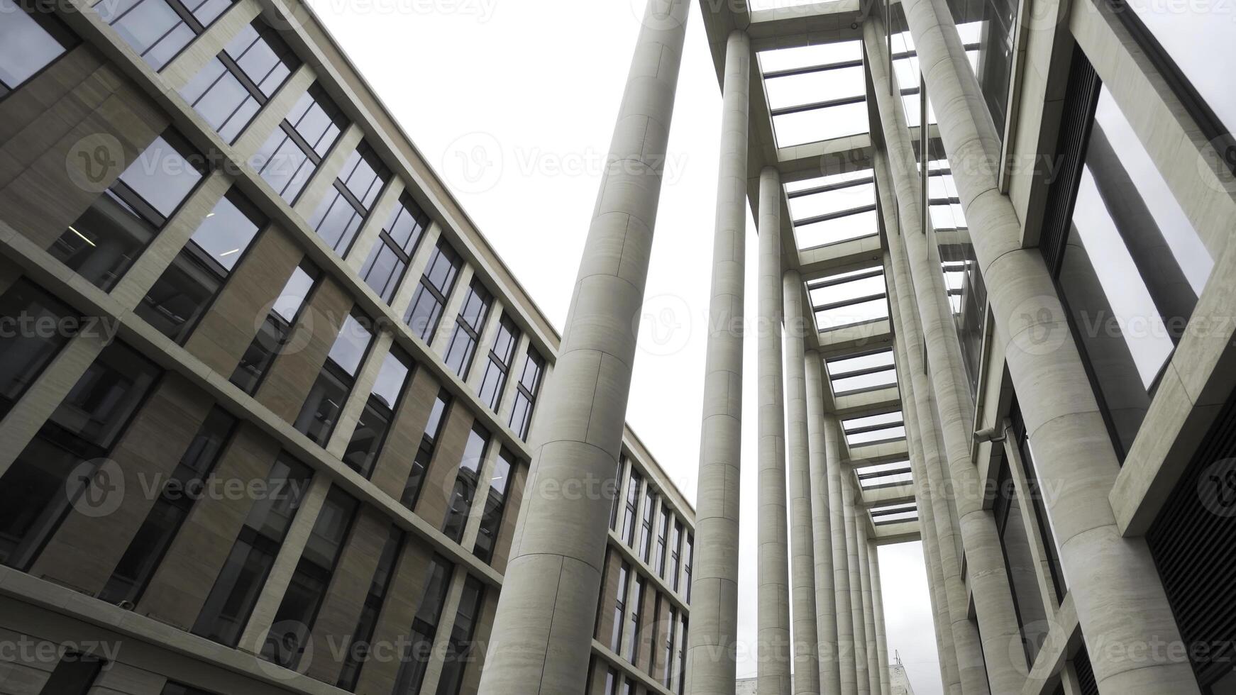 Fassade von ein Gebäude mit Marmor Säulen. Aktion. Unterseite Aussicht von ein modern architektonisch Komplex, Neu Gebäude mit Licht Beige Säulen und groß Fenster. foto