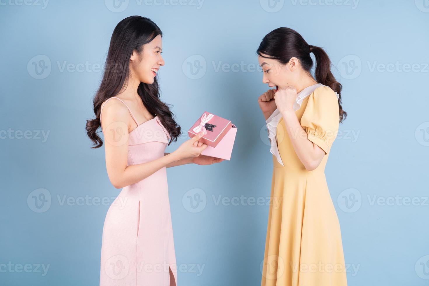 zwei junge asiatische frauen tragen kleid auf blauem hintergrund foto
