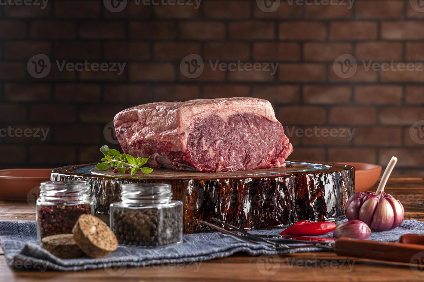 Raw Strip Loin Beef argentinische Chorizo auf einem holzgeharzten Schneidebrett mit Gewürzen. Holztisch mit Ziegelsteinwandhintergrund. foto