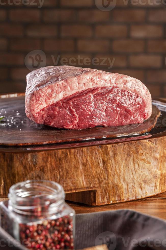 Raw Cap Rump Beef - brasilianischer Picanha - auf einem holzgeharzten Schneidebrett auf einem Ziegelsteinwandhintergrund. foto