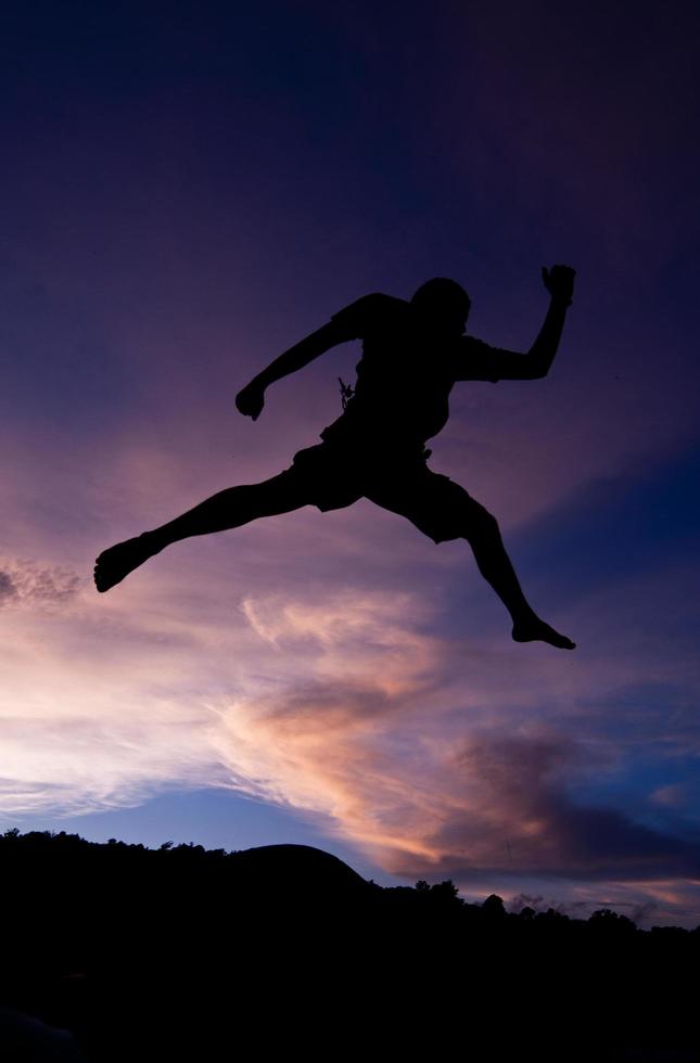 Silhouette glückliches Springen gegen schön im Sonnenuntergang. Freiheit, Genusskonzept foto