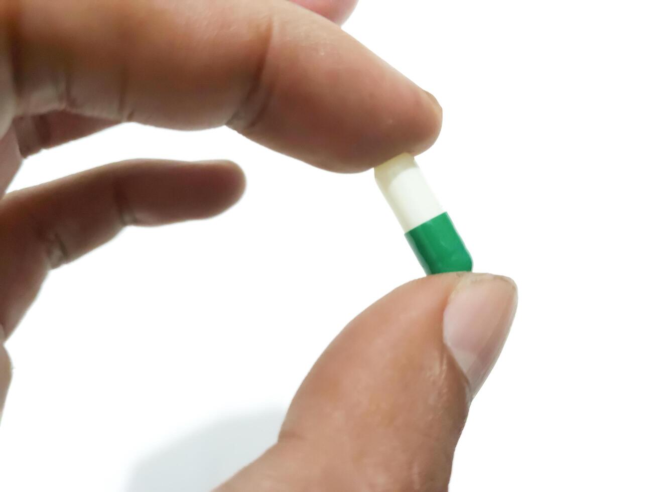 Finger von ein Hand halten ein Kapsel Pille isoliert auf ein Weiß Hintergrund foto