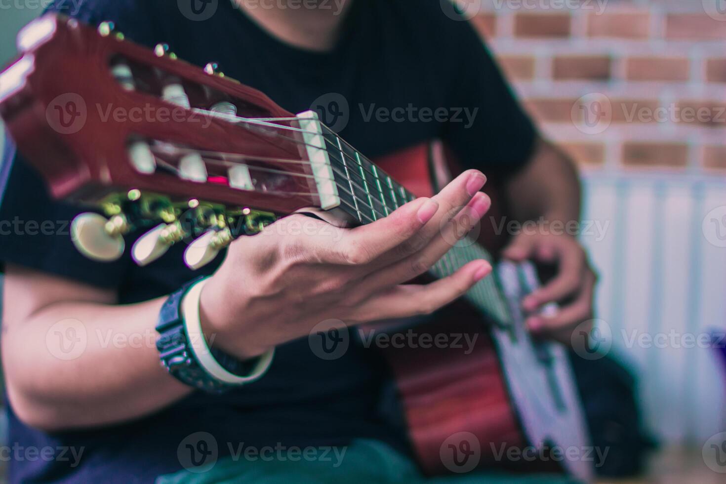 ein jung Mann ist üben spielen Gitarre im ein Musik- trainieren Zimmer Vor durchführen im bestellen zu reduzieren das Fehler von spielen Gitarre auf Bühne. schließen oben jung Mann ist halten Gitarre Akkorde zum ausüben. foto