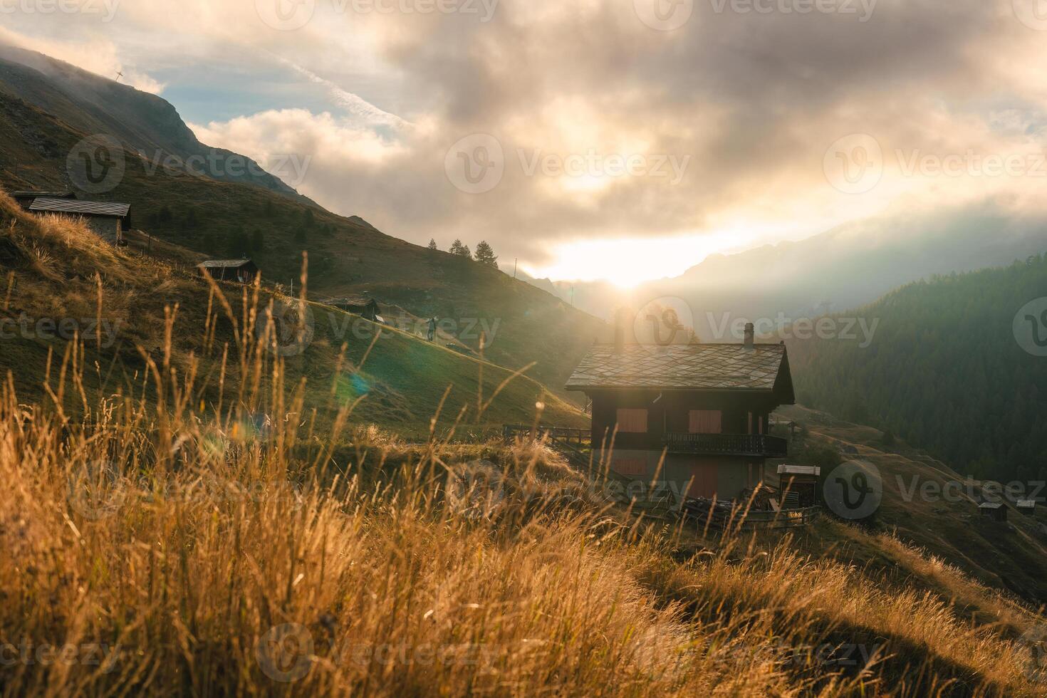 Sonnenaufgang scheint Über hölzern Hütte auf Hügel unter das schweizerisch Alpen im Berg Dorf beim Schweiz foto