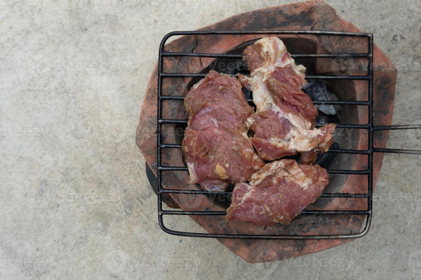 über Aussicht von drei Stücke von frisch Schweinefleisch gegrillt auf ein Gummi Grill. Platz auf das Holzkohle Herd. foto