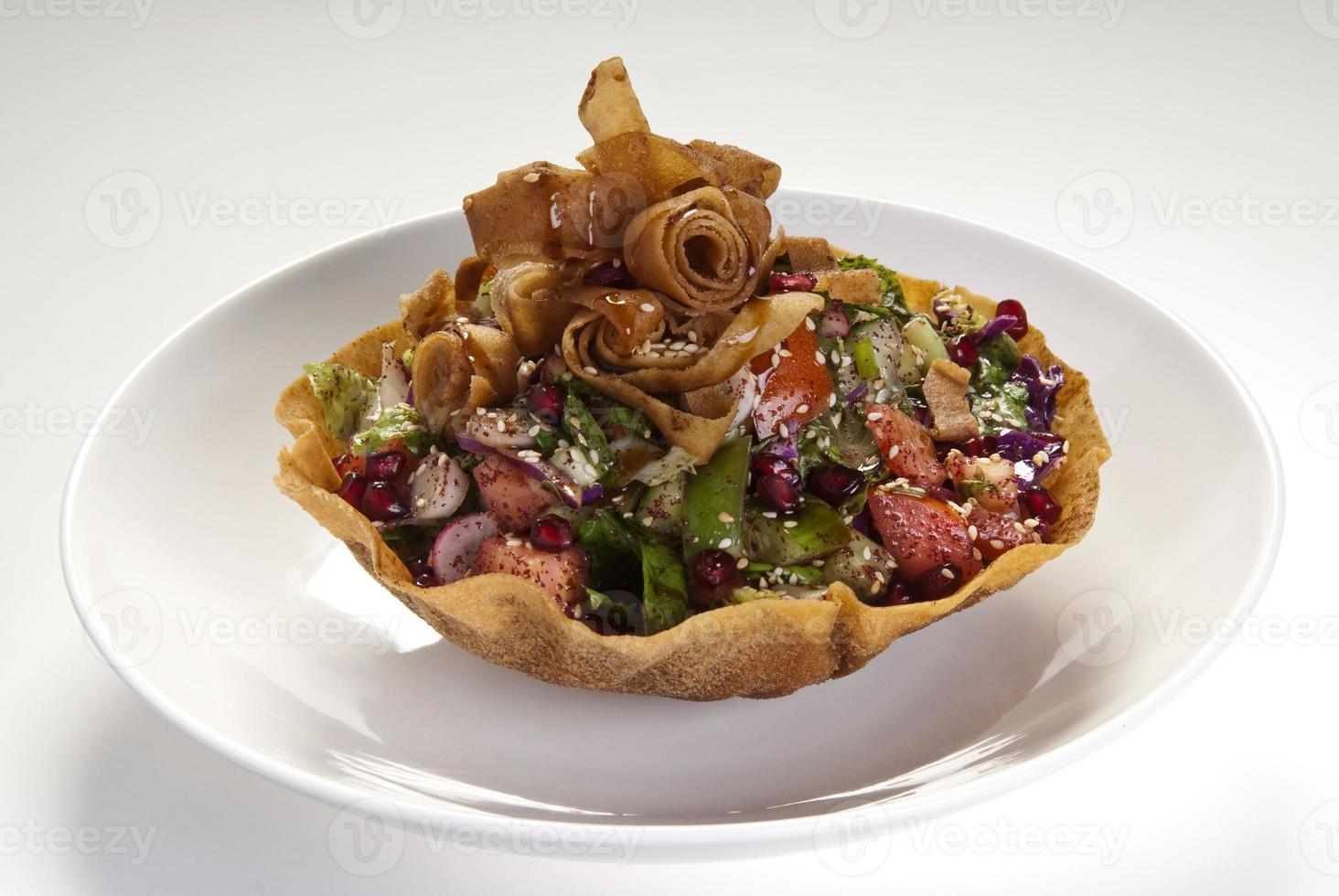 Köstlicher Fattoush oder arabischer Salat mit Pita-Croutons, frischem Gemüse und Kräutern, auf weißem Teller. orientalischer Brotsalat. einfaches und gesundes authentisches Rezept. foto