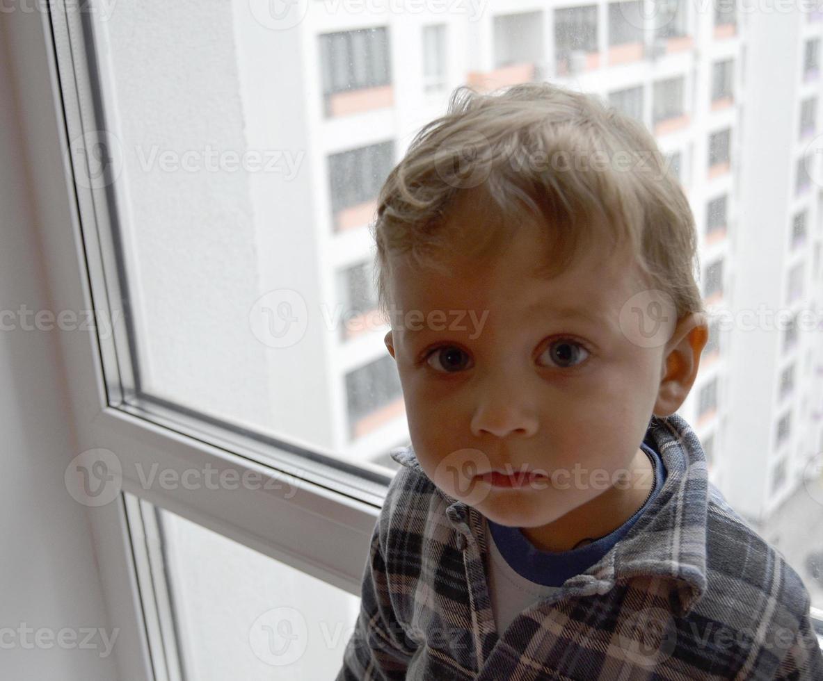 schönes Baby mit Kindergesicht posiert Fotograf in der Nähe von Fenster foto