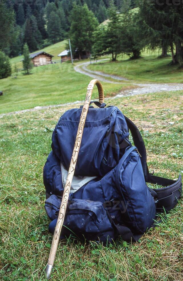 ein Rucksack und ein Stock Sitzung auf das Gras foto