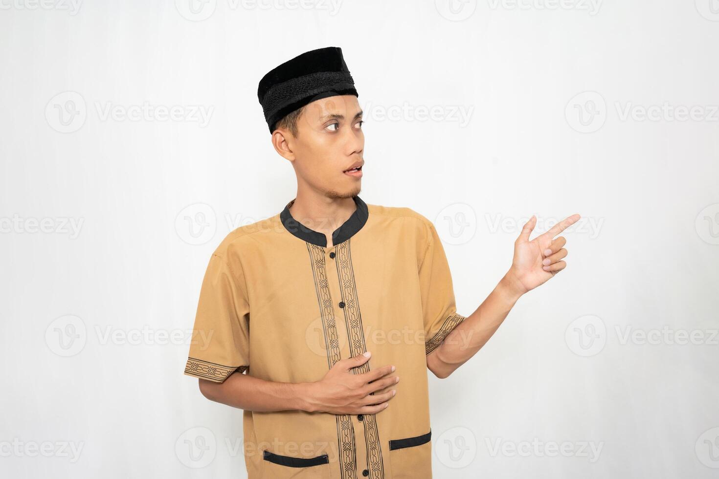 asiatisch Muslim Mann tragen braun Muslim Kleider lächelnd glücklich während zeigen beim ein leeren Raum. isoliert Weiß Hintergrund. foto
