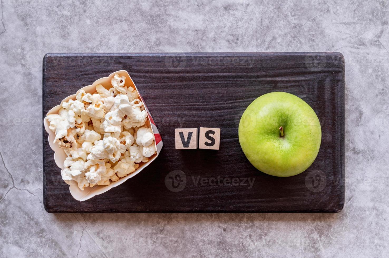 Popcorn versus Apfel Draufsicht auf dunklem Hintergrund foto