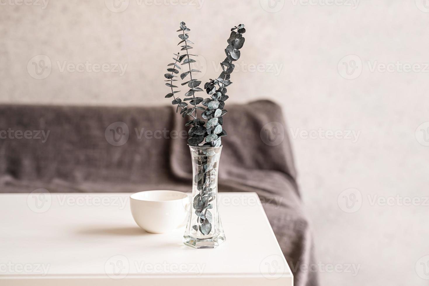 Eukalyptus in einer Vase mit einer Tasse Kaffee auf weißem Tisch foto