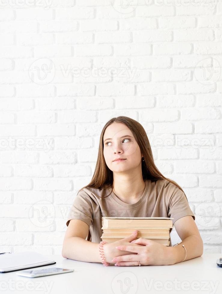 deprimiertes Schulmädchen mit einem Stapel Bücher, die wegschauen foto