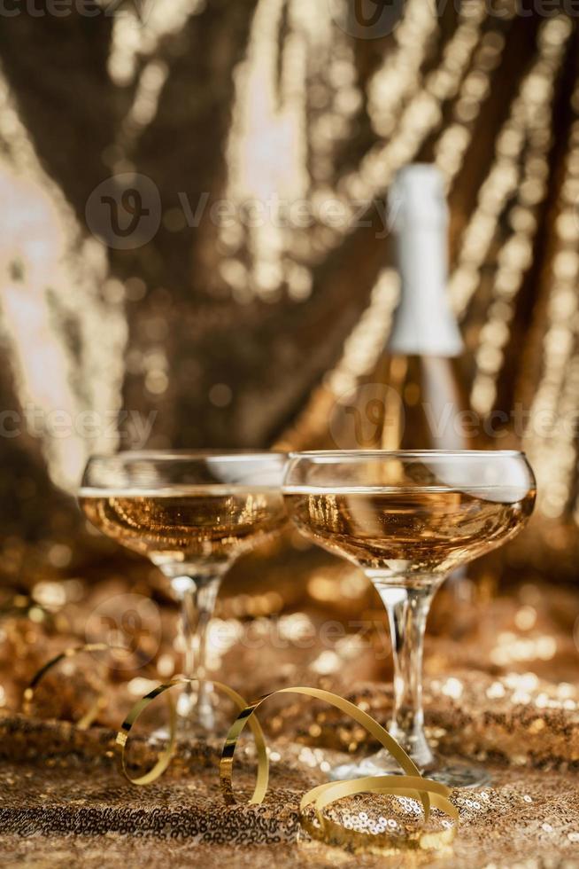 zwei Sektflöte mit glänzender Flasche auf goldenem glänzendem Hintergrund foto