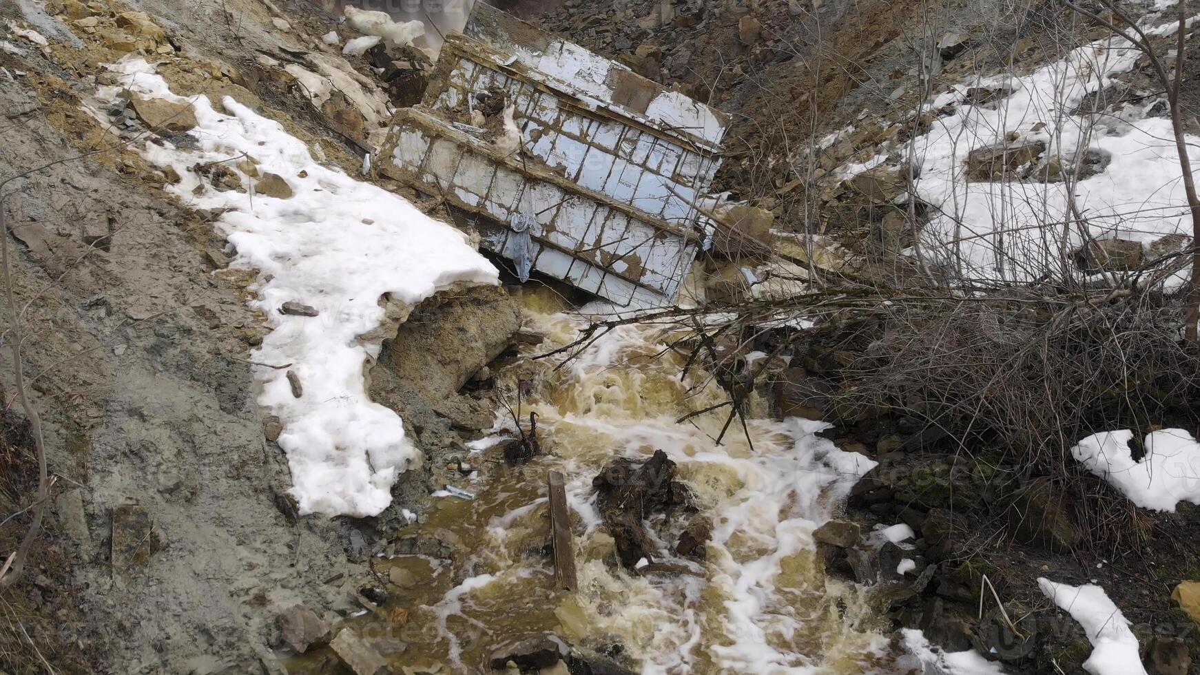 Antenne zum felsig Steinbruch mit schmutzig Wasser Strom fallen Nieder und alt Müll auf das Boden, verschmutzt Umfeld, Ökologie Konzept. Aktie. Müll geworfen Weg auf das felsig Oberfläche von Steinbruch. foto