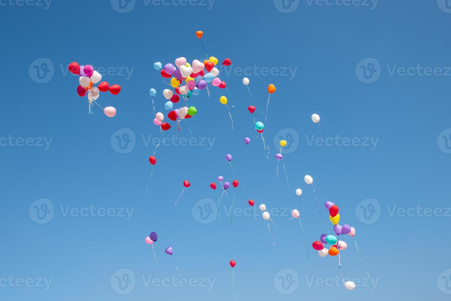 Ballons in verschiedenen Farben, die in den blauen Himmel fliegen foto