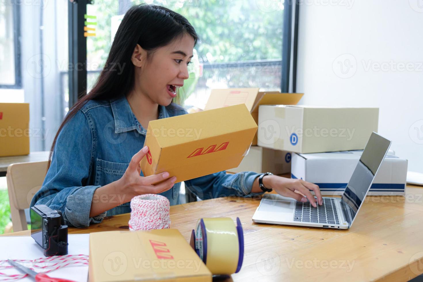 der paketzusteller sucht mit einem laptop die produktnummer. sie hielt das Paket in der Hand und lächelte glücklich. foto