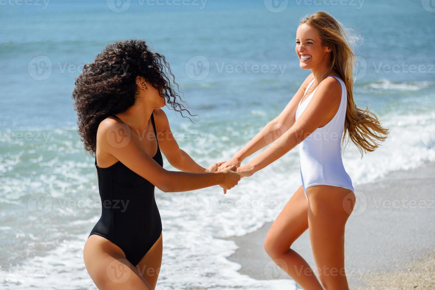 zwei frauen im badeanzug amüsieren sich am strand foto