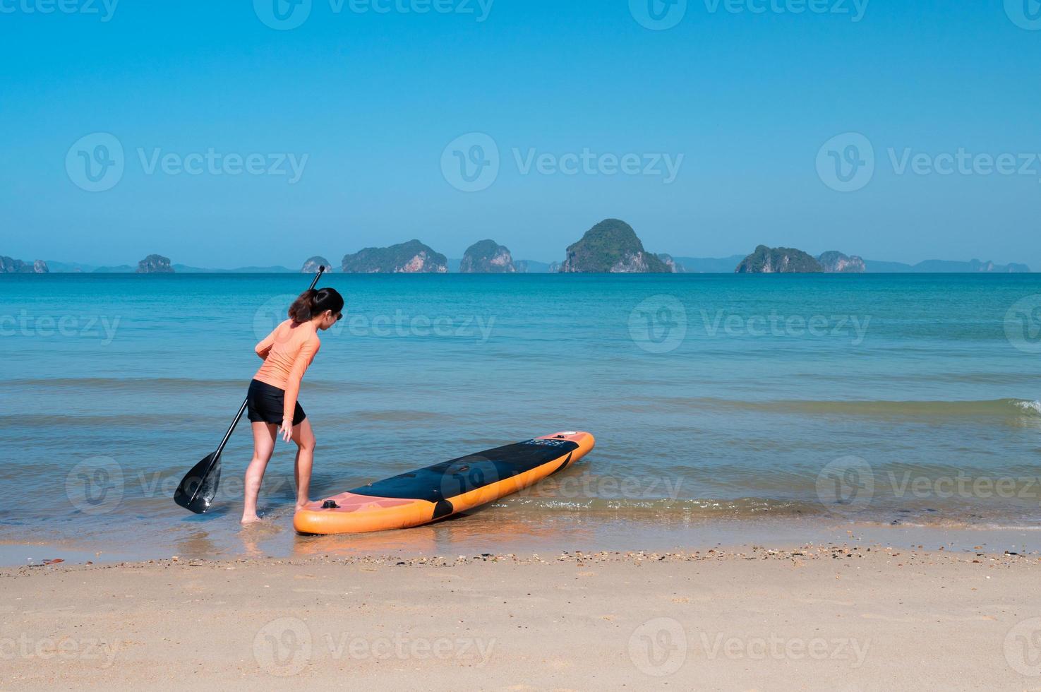 Junge sportliche Frau, die an einem sonnigen Tag der Sommerferien Stand-Up-Paddle-Board auf dem blauen Meer spielt foto