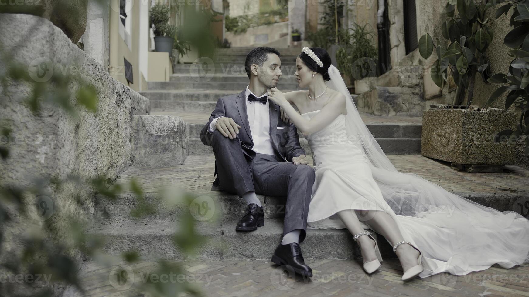 süß Gehen Paar Sitzung auf das Stufen. Aktion. glücklich Jungvermählten filmen auf das Straße im Hochzeit Kostüme. foto