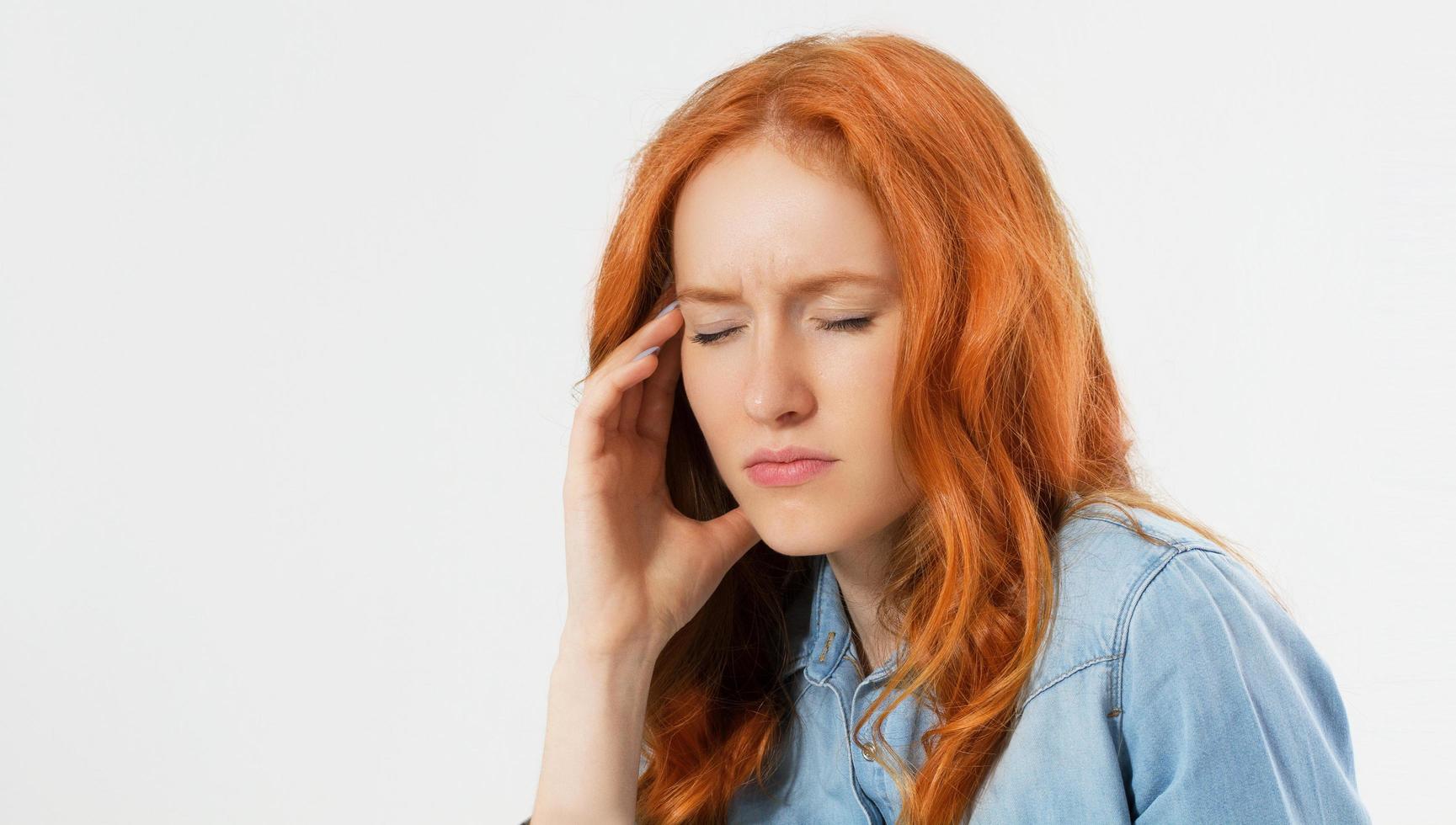 Junge hoffnungslose Frau mit roten Haaren, die an Depressionen leidet und einen Nervenzusammenbruch hat, der ihren Kopf auf isoliertem Hintergrund hält, Kopierraum, weibliche Migräne foto