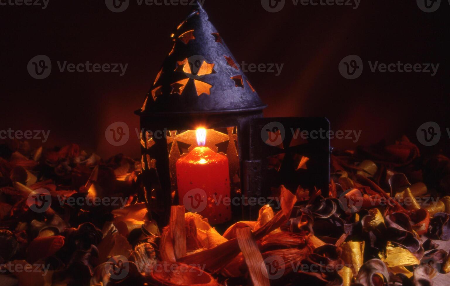 ein Kerze ist zündete im ein Laterne umgeben durch Blätter foto