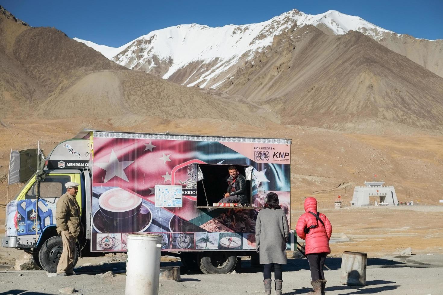 khunjerab pass, pakistan, 2017 - frauen touristen sprechen mit einem mann, der an der grenze zu pak-china lebensmittel verkauft. foto