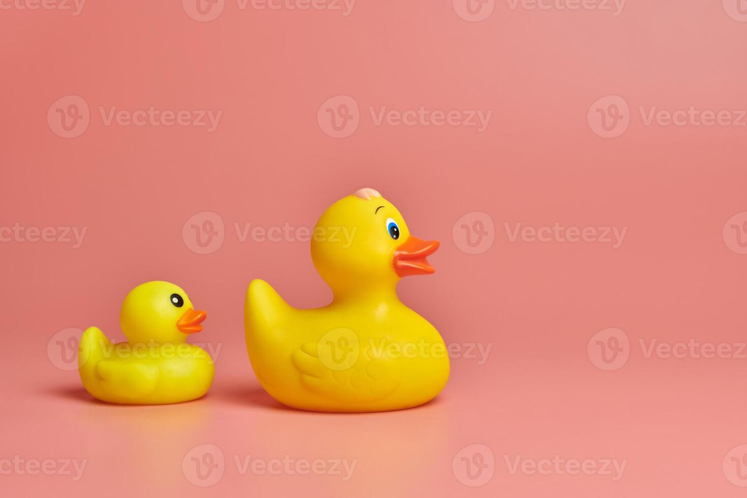 zwei gelbe gummienten spielzeug, kopierraum. süßes lustiges badespielzeug, minimales kidult-konzept. rosa Hintergrund. foto