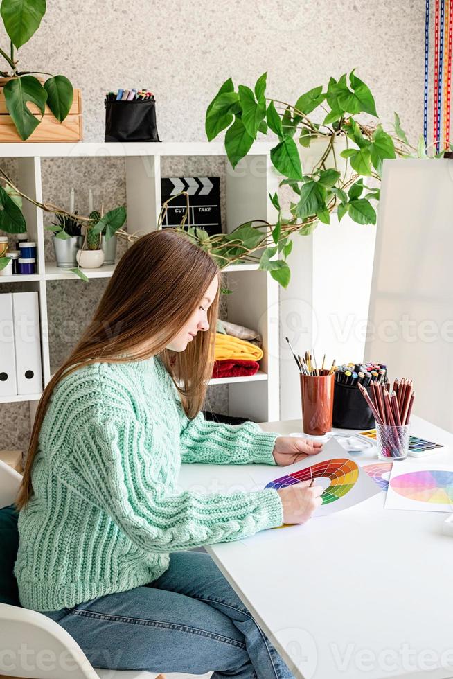 junge Teenager-Künstlerin mit Farbpalette, die in ihrem Studio arbeitet? foto