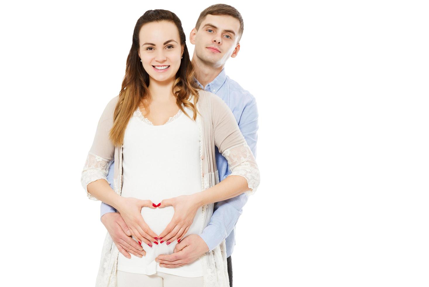 glückliches Paar, das mit den Händen eine Herzform auf dem schwangeren Bauch macht. Konzept der Schwangerschaft, ein Baby erwarten, Liebe, Fürsorge foto