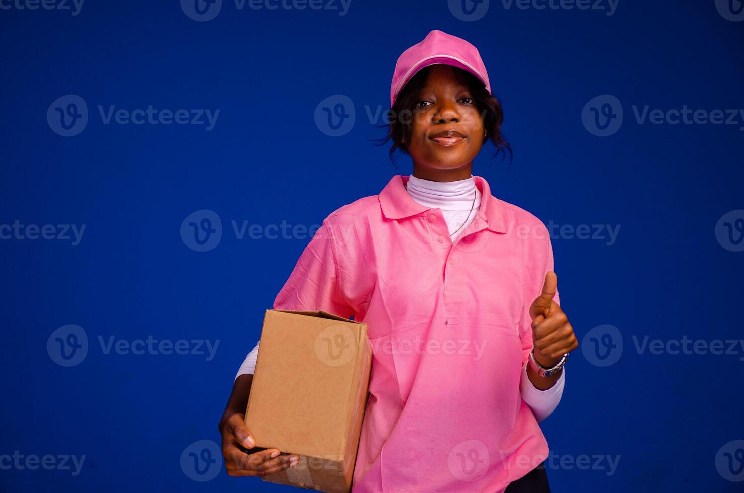 schön afrikanisch weiblich Kurier Arbeiter halten ein Kasten, tut ein Daumen oben Geste foto