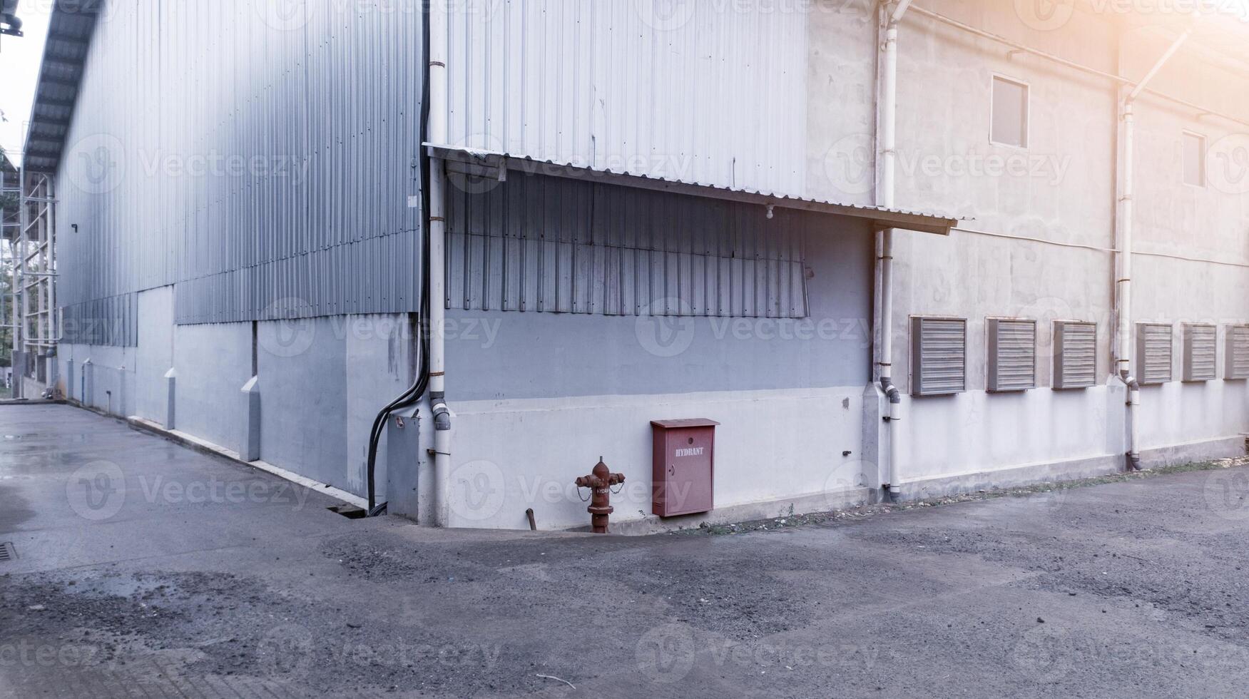 industriell Gebäude mit Stahl Dach Konstruktion und Eingerichtet Auspuff Fans auf das Wand, und mit Hydrant Installation. foto