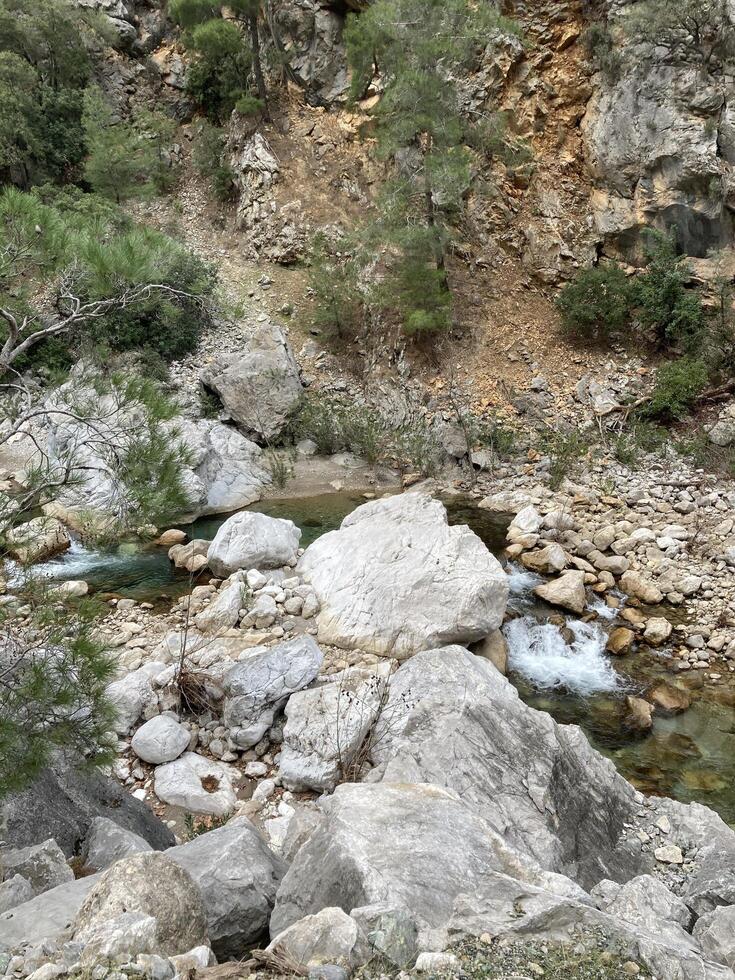 ein klein Kristall klar Berg Fluss fließt unter das Steine, finden es ist Weg foto
