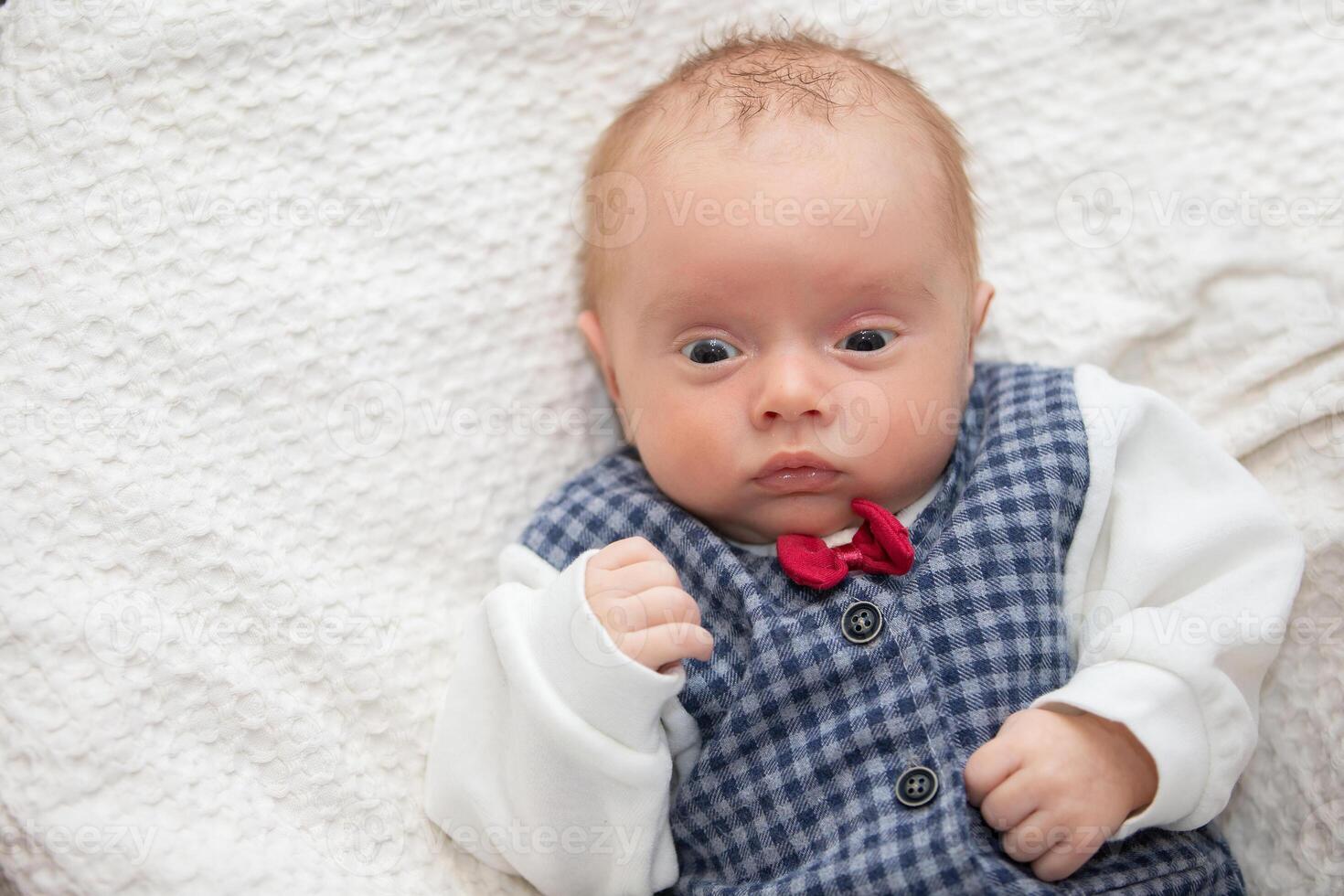 Porträt von ein Neugeborene Baby tragen ein elegant Weste mit ein rot Bogen binden. foto