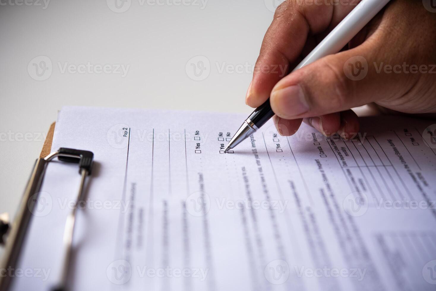 Nahansicht von Hand Schreiben Papier beim das Schreibtisch mit Stift und lesen Bücher beim Tabelle mit Arbeiten im Büro foto