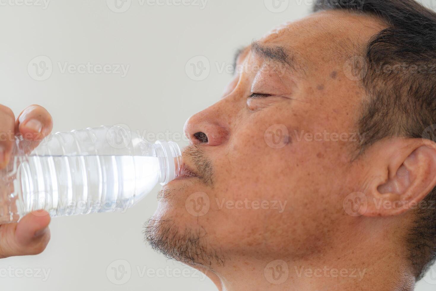 Glück von männlich Alten halten ein Flasche von Wasser. Senior Menschen Trinken frisch Mineral Wasser. foto