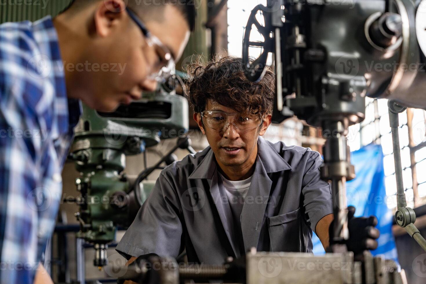 asiatisch Arbeiter im Produktion Pflanze Bohren beim Maschine. Fachmann Arbeiter in der Nähe von Bohren Maschine auf Fabrik. Fertigstellung Metall Arbeiten intern Stahl Oberfläche auf Drehbank Schleifer Maschine mit fliegend Funken. foto