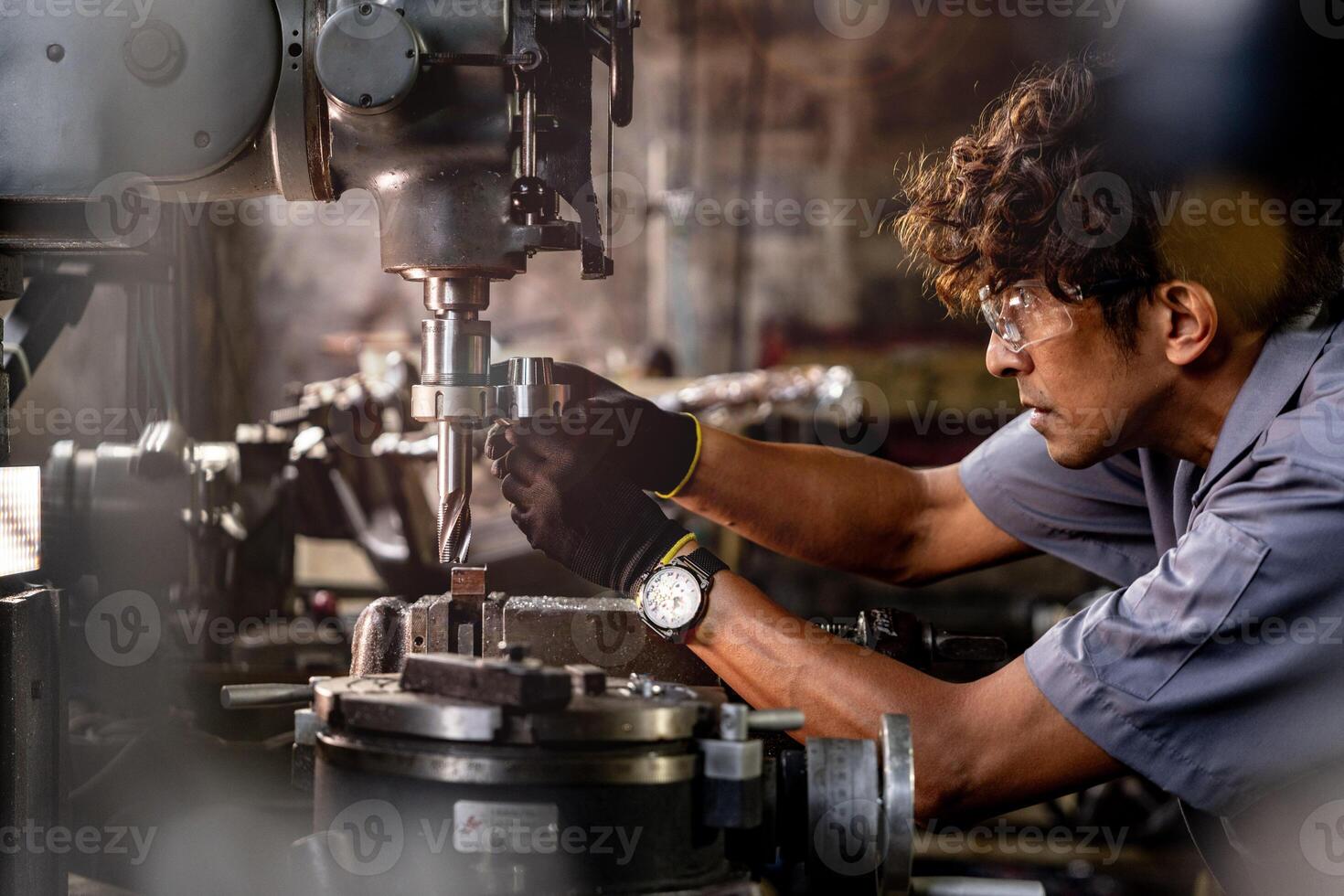 asiatisch Arbeiter im Produktion Pflanze Bohren beim Maschine. Fachmann Arbeiter in der Nähe von Bohren Maschine auf Fabrik. Fertigstellung Metall Arbeiten intern Stahl Oberfläche auf Drehbank Schleifer Maschine mit fliegend Funken. foto