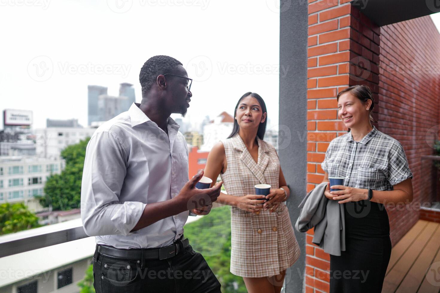 Mannschaft von Geschäft Menschen Clever Mann und Frauen Stand beim draussen Terrasse Gebäude und sich unterhalten zusammen mit Frühstück Essen und Kaffee auf das Hand im gut Gefühl mit Stadt Raum Gebäude. Geschäft Morgen. foto