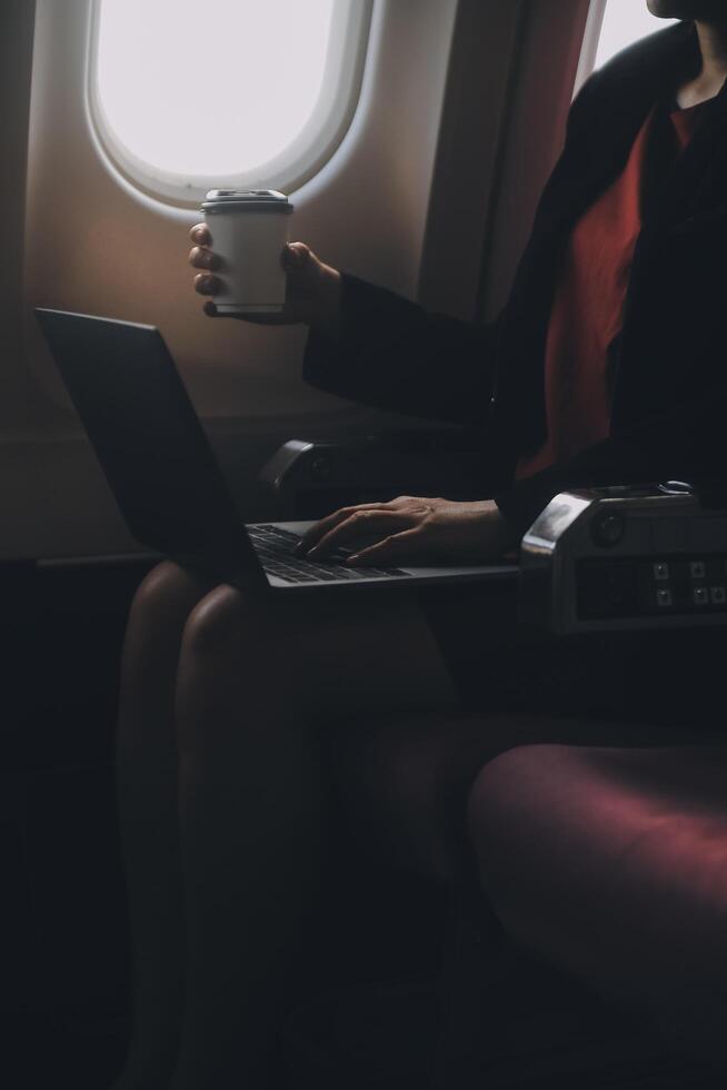 blond weiblich Tourist Überprüfung eingehend Benachrichtigung auf Smartphone Sitzung auf Sitz von Flugzeug mit Netbook.jung Geschäftsfrau Teilen Medien von Telefon auf Laptop Computer während Flugzeug Flug foto