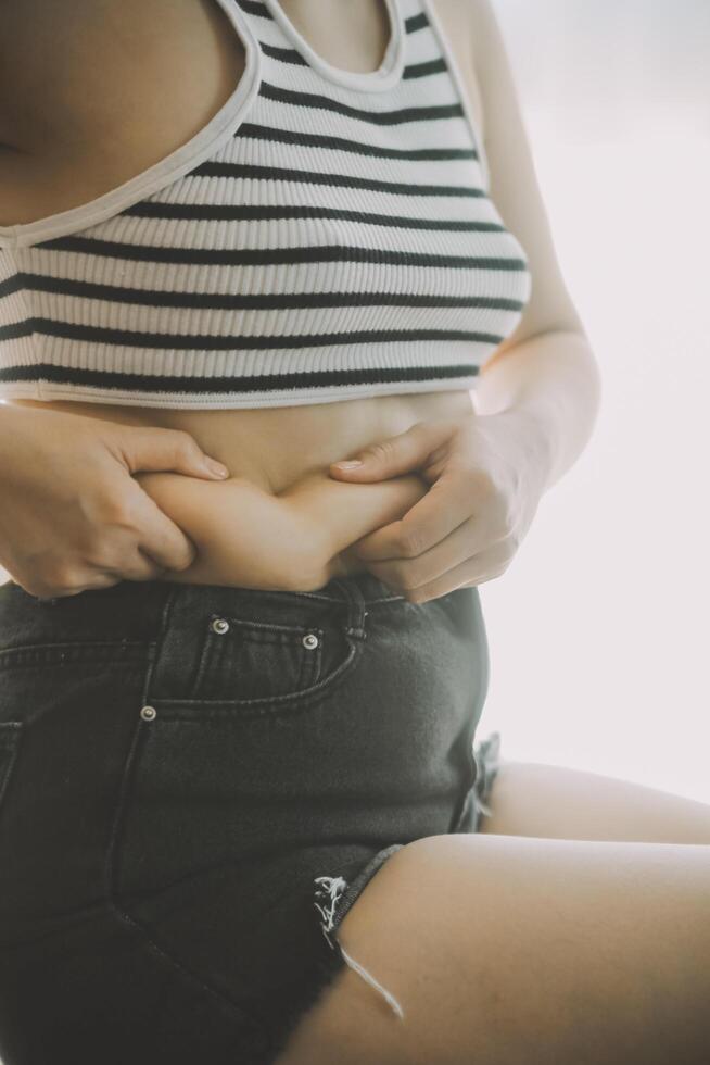 Frauen Körper Fett Bauch. fettleibig Frau Hand halten übermäßig Bauch fett. Diät Lebensstil Konzept zu reduzieren Bauch und gestalten oben gesund Bauch Muskel. foto